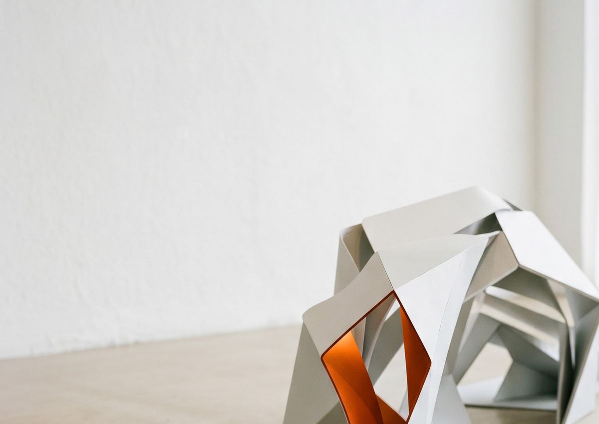 Escultura de papel dobrado em branco e laranja em um ambiente claro